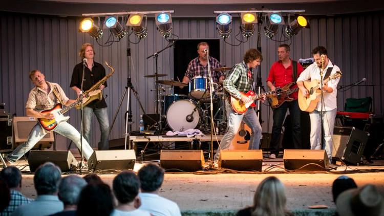 Die Band mit Saxophon auf einer Bühne vor Publikum