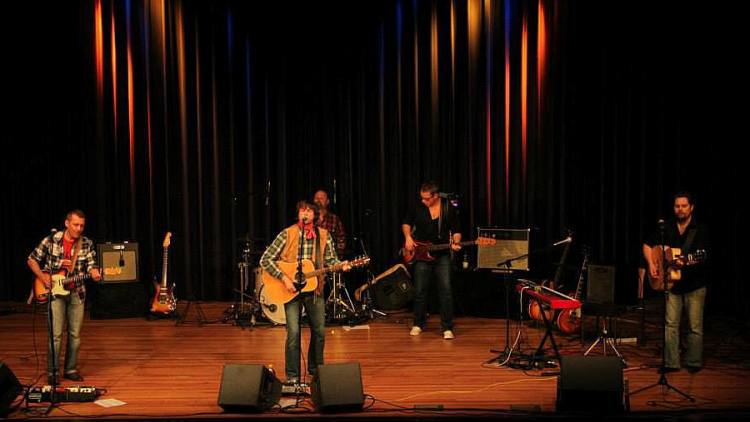 Die Band auf einer großen Bühne vor dunklem Vorhang