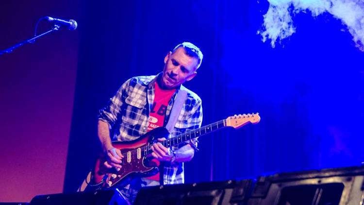 Gitarrist mit roter E-Gitarre in blauem Licht